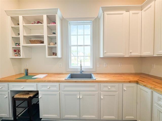 kitchen featuring white cabinetry, sink, and wooden counters