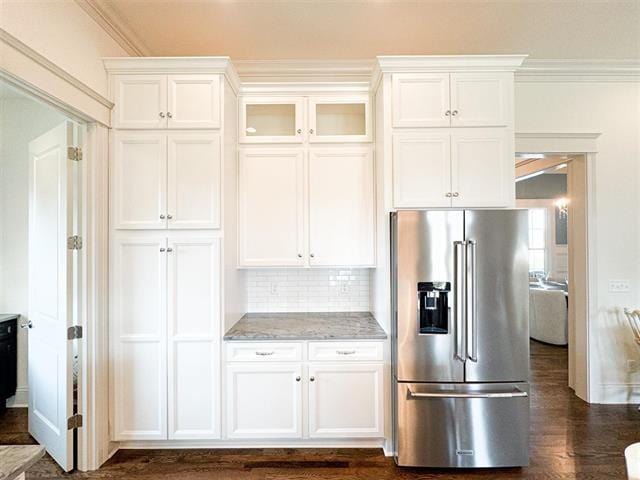 kitchen with crown molding, light stone counters, high quality fridge, white cabinets, and backsplash