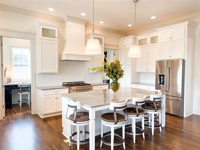 kitchen with white cabinetry, hanging light fixtures, stainless steel appliances, custom range hood, and a kitchen island