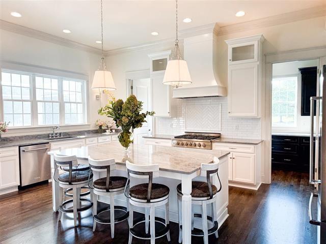 kitchen with premium range hood, decorative light fixtures, dishwasher, white cabinets, and a center island