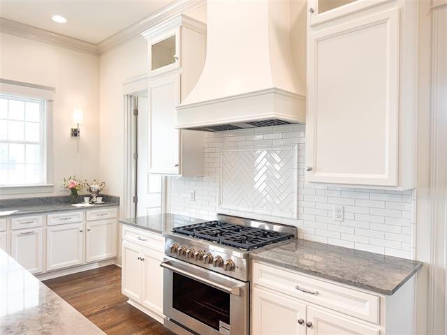 kitchen featuring stainless steel range, light stone countertops, custom exhaust hood, and white cabinets