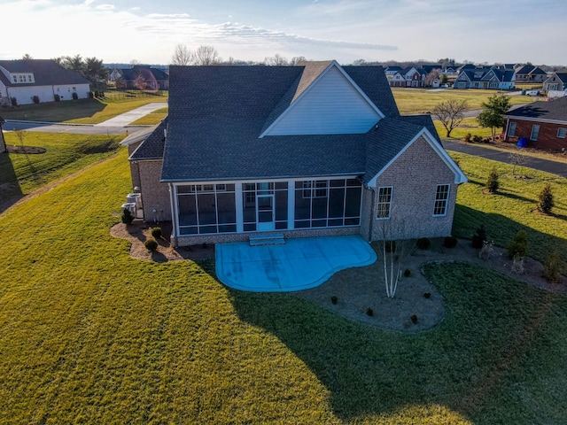 rear view of property featuring a patio area, a sunroom, and a lawn