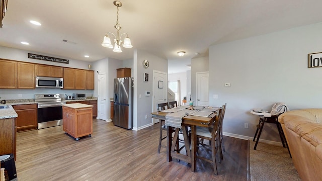 kitchen featuring decorative light fixtures, dark hardwood / wood-style floors, a center island, appliances with stainless steel finishes, and a chandelier