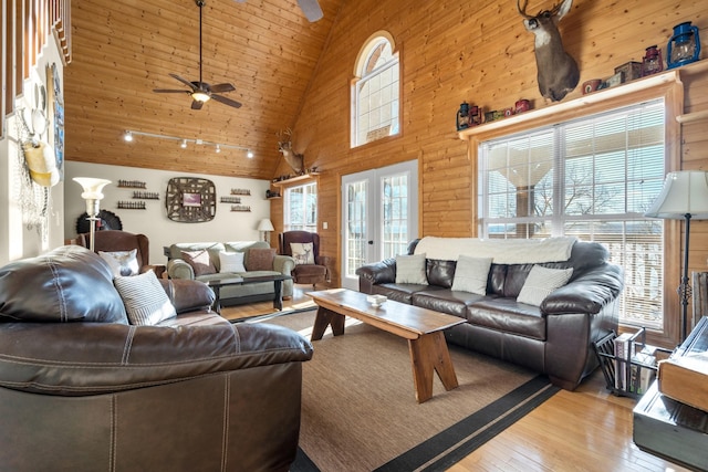 living room with french doors, light hardwood / wood-style flooring, high vaulted ceiling, and a wealth of natural light