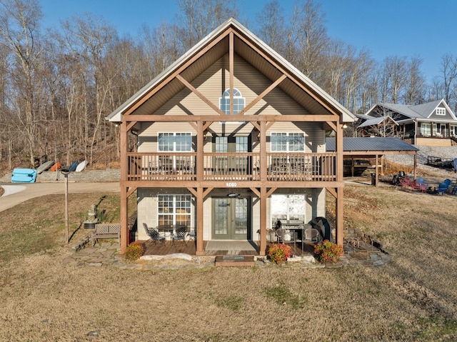 rear view of house featuring a lawn, a wooden deck, and french doors