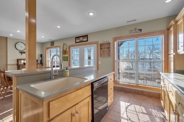 kitchen with a wealth of natural light, sink, light brown cabinets, black dishwasher, and a center island with sink