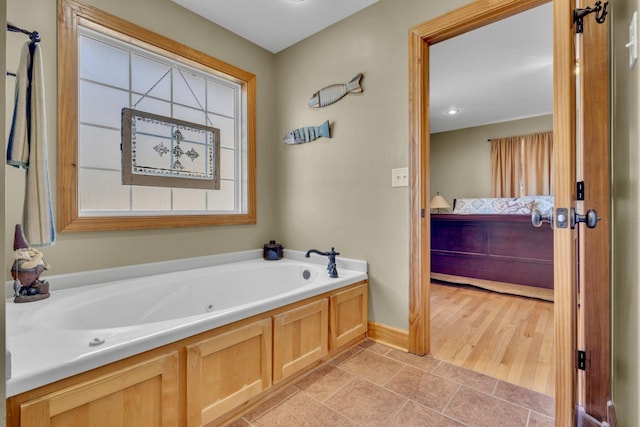 ensuite bathroom featuring connected bathroom, baseboards, and a bath