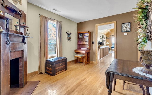 interior space with light wood-style floors, a tile fireplace, visible vents, and baseboards