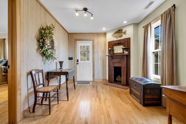 entryway featuring a fireplace with raised hearth, light wood finished floors, visible vents, and a healthy amount of sunlight