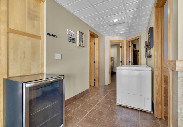 corridor featuring an ornate ceiling, beverage cooler, and baseboards