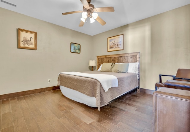 bedroom with a ceiling fan, baseboards, visible vents, and wood finished floors