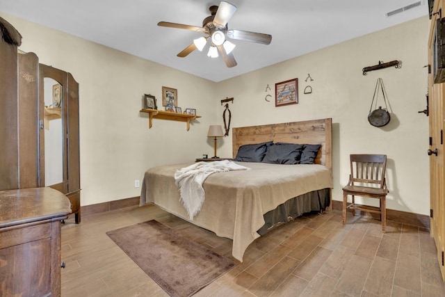 bedroom featuring a ceiling fan, baseboards, visible vents, and wood finished floors