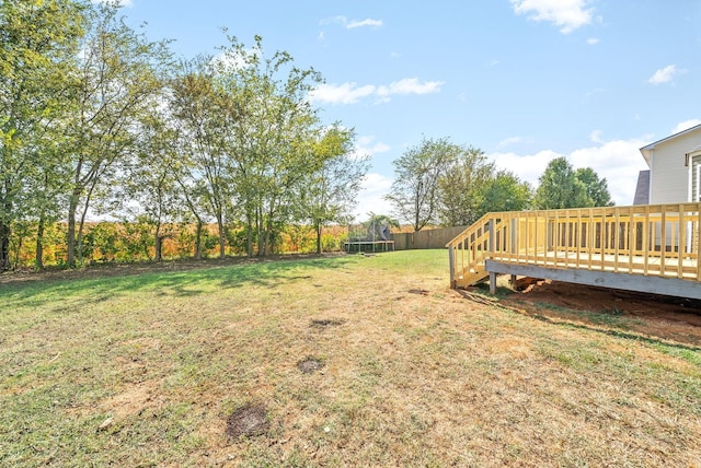 view of yard featuring a trampoline and a wooden deck