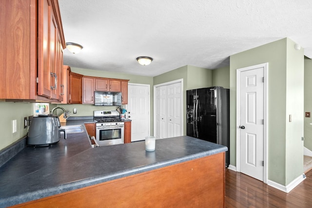 kitchen with kitchen peninsula, dark hardwood / wood-style flooring, a textured ceiling, sink, and black appliances