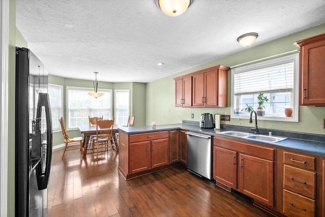 kitchen featuring sink, stainless steel dishwasher, kitchen peninsula, pendant lighting, and black refrigerator