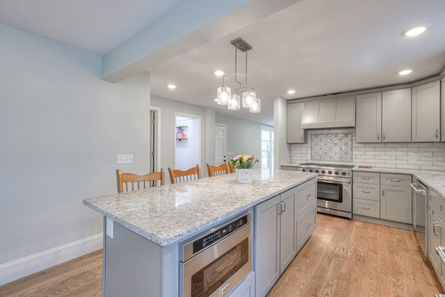 kitchen with a kitchen breakfast bar, tasteful backsplash, light hardwood / wood-style flooring, a kitchen island, and appliances with stainless steel finishes