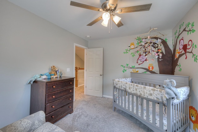 bedroom with ceiling fan, a crib, and light carpet