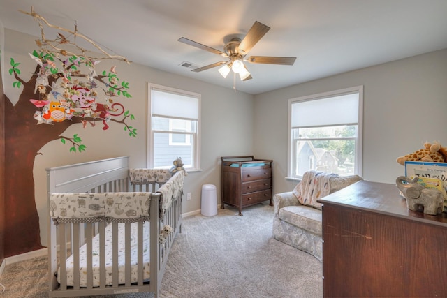 carpeted bedroom with a nursery area and ceiling fan