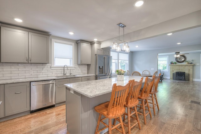 kitchen featuring a center island, a tile fireplace, sink, a kitchen bar, and stainless steel appliances