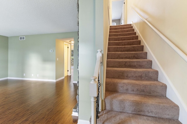 staircase featuring wood-type flooring and a textured ceiling