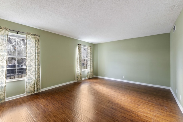 empty room featuring dark hardwood / wood-style flooring and a textured ceiling