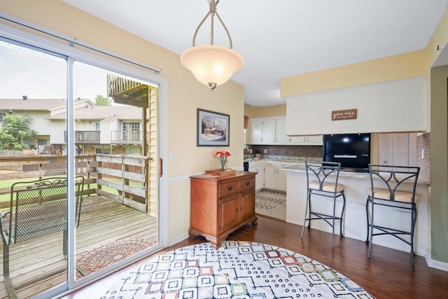 kitchen with tasteful backsplash, a breakfast bar, pendant lighting, white cabinets, and fridge