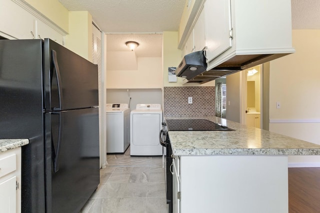 kitchen featuring washing machine and clothes dryer, white cabinetry, black fridge, a textured ceiling, and decorative backsplash