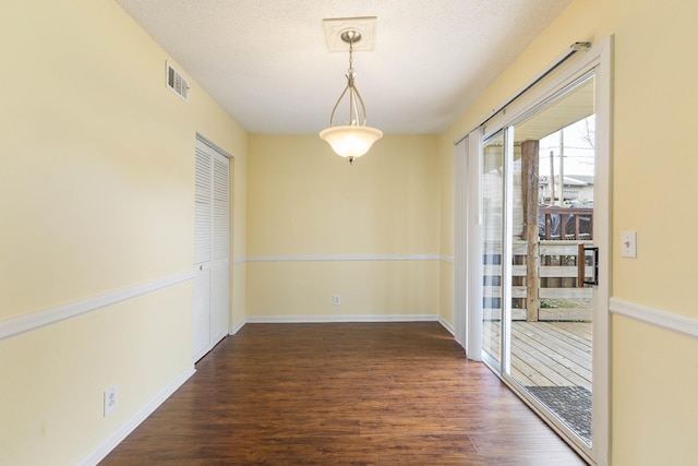 unfurnished dining area with a textured ceiling and dark wood-type flooring