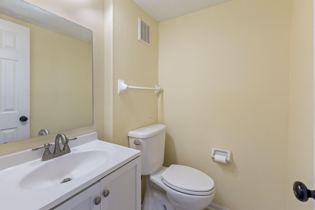 bathroom featuring vanity, toilet, and a textured ceiling