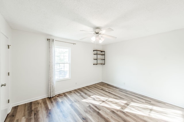 unfurnished room featuring ceiling fan, light wood-type flooring, and a textured ceiling