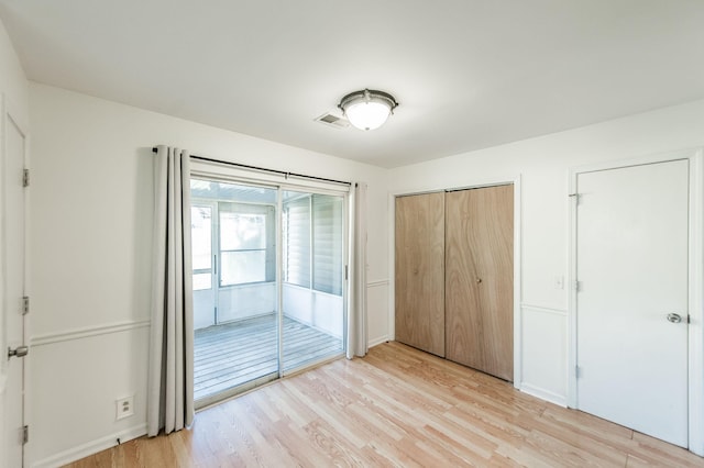 unfurnished bedroom featuring access to exterior, a closet, and light hardwood / wood-style flooring