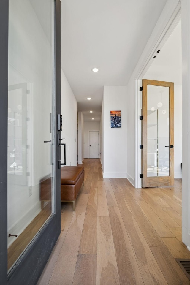 hall with french doors and light wood-type flooring