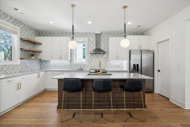 kitchen featuring backsplash, wall chimney range hood, decorative light fixtures, white cabinets, and a kitchen island