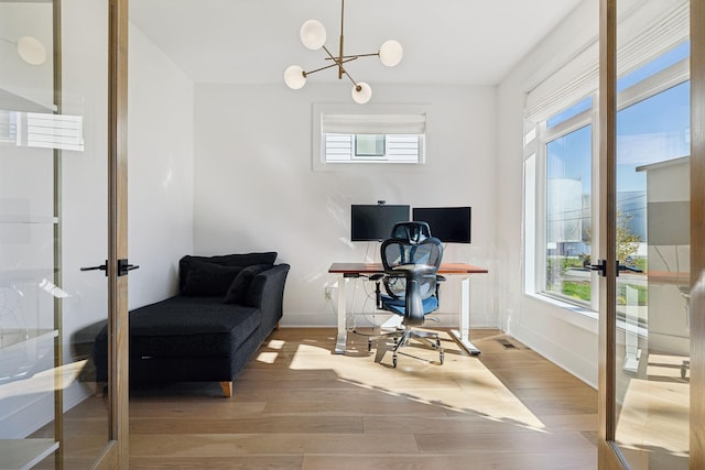 office area featuring french doors, light wood-type flooring, and an inviting chandelier