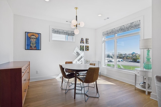 dining space with a notable chandelier and light wood-type flooring