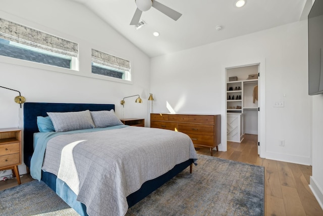 bedroom with hardwood / wood-style floors, lofted ceiling, a walk in closet, ceiling fan, and a closet