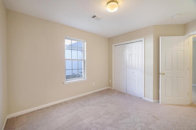 unfurnished bedroom featuring light colored carpet and a closet