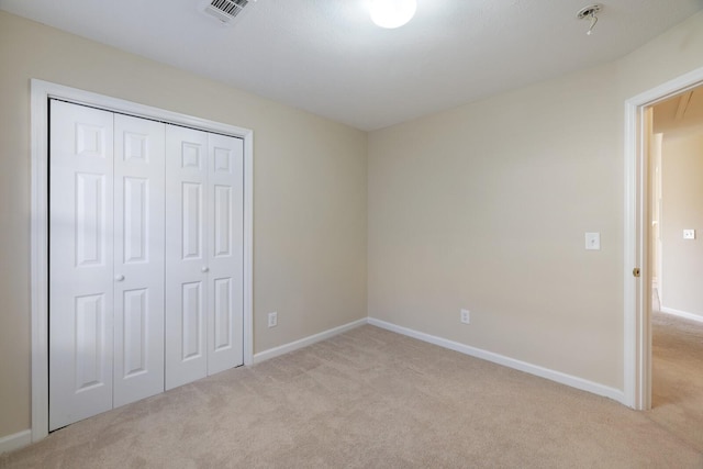 unfurnished bedroom with light colored carpet and a closet