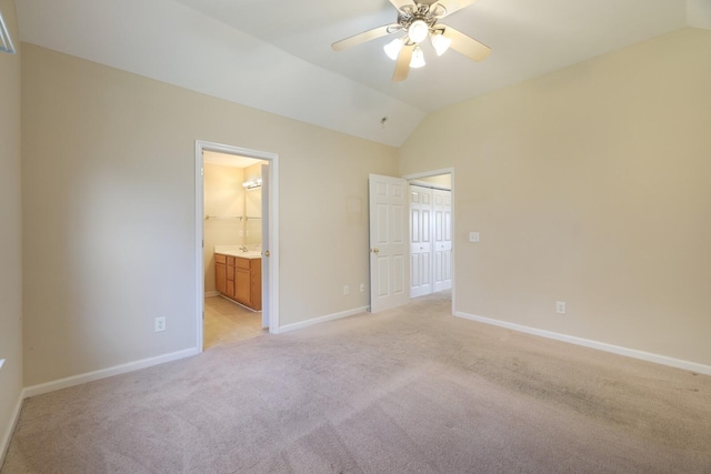 unfurnished bedroom featuring ceiling fan, a walk in closet, light carpet, and vaulted ceiling