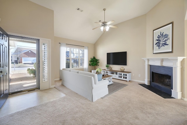 carpeted living room with ceiling fan and high vaulted ceiling