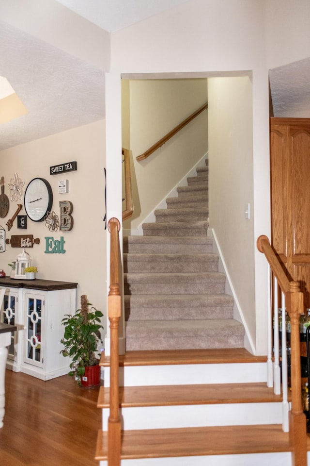 stairway with indoor bar and hardwood / wood-style floors