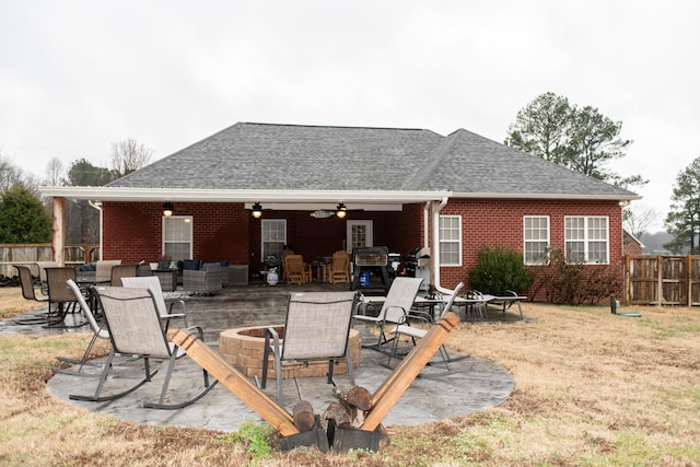 rear view of house with ceiling fan, a yard, a fire pit, and a patio