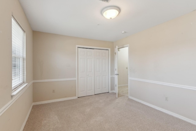 unfurnished bedroom featuring light colored carpet, multiple windows, and a closet