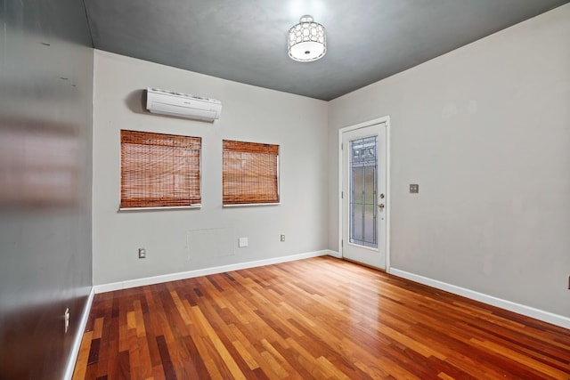 spare room featuring an AC wall unit and wood-type flooring