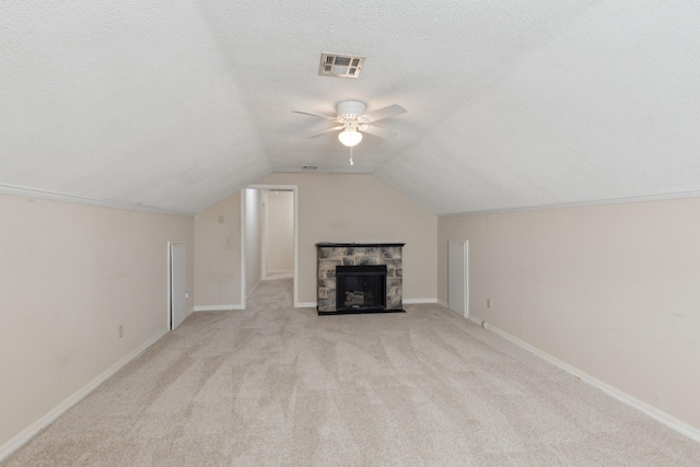 bonus room featuring vaulted ceiling, ceiling fan, a fireplace, a textured ceiling, and light colored carpet