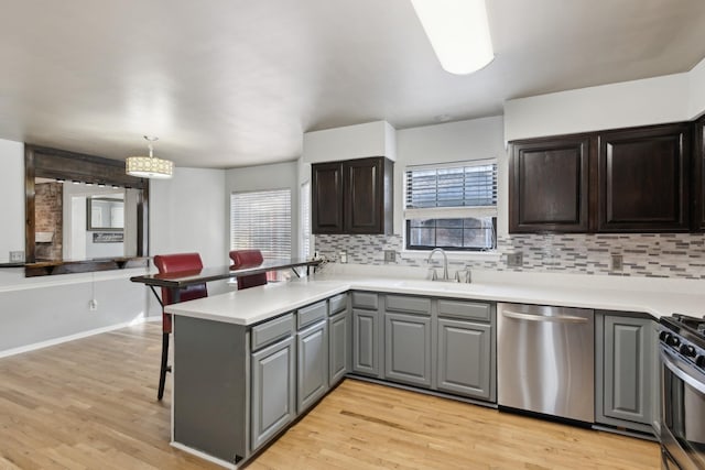 kitchen featuring pendant lighting, sink, decorative backsplash, kitchen peninsula, and stainless steel appliances