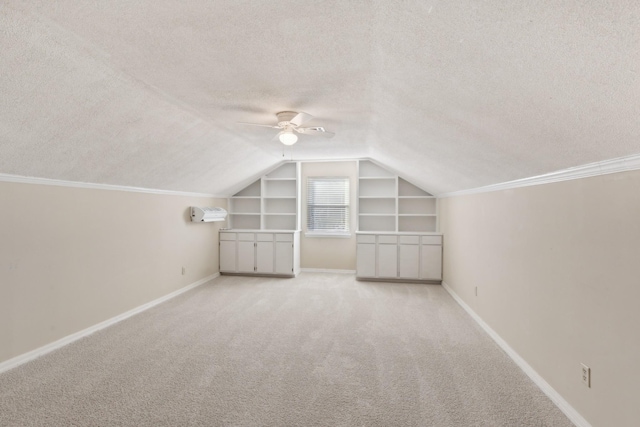 additional living space featuring ceiling fan, built in features, vaulted ceiling, a textured ceiling, and light carpet