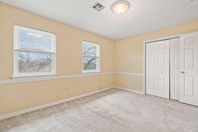 unfurnished bedroom featuring light carpet and a closet