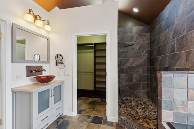 bathroom featuring a tile shower, vanity, and lofted ceiling