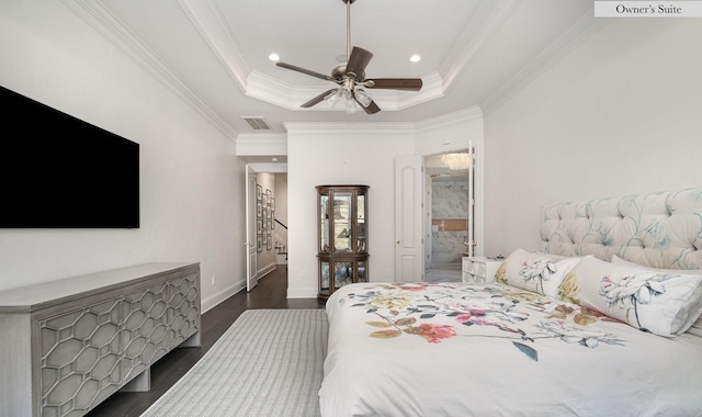 bedroom with ceiling fan, ornamental molding, dark hardwood / wood-style floors, a tray ceiling, and ensuite bathroom